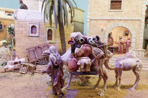 Joulupienoismalli, jossa vanhoja rakennuksia, ihmisiä, aaseja tavaroita selässään ja palmu.